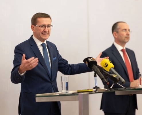 Markus Achleitner vor einem Rednerpult mit Mikrofonen