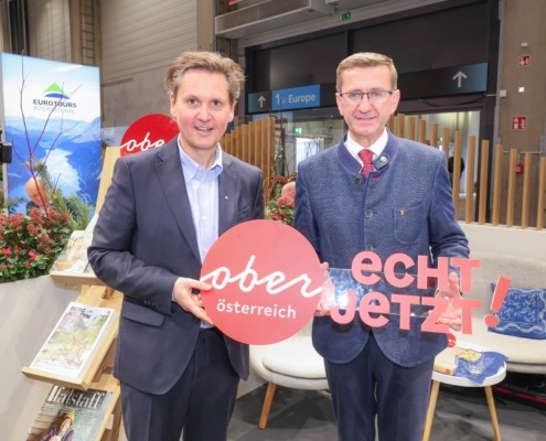 Zwei Herren im Anzug halten ein Plakat. Auf dem Plakat steht "Oberösterreich: echt jetzt"