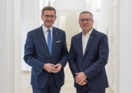 Zwei Männer stehen nebeneinander und lächeln in die Kamera.