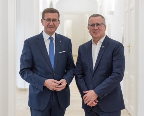 Zwei Männer stehen nebeneinander und lächeln in die Kamera.