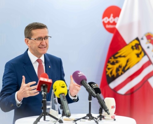 ein Mann steht auf einem Tisch mit vielen Mikrofonen und redet.