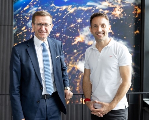 Zwei Herren stehen vor einer Wand und lächeln in die Kamera