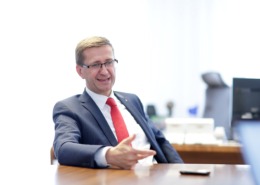 Ein Herr sitzt am Schreibtisch und redet.