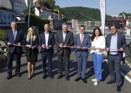 Sieben Personen stehen in Linz mit einem Band in der Hand.