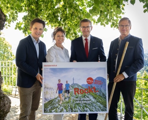 Vier Personen stehen in der Natur und halten ein Plakat in der Hand.