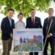 Vier Personen stehen in der Natur und halten ein Plakat in der Hand.