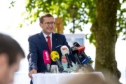 Wirtschafts- und Tourismus-Landesrat Markus Achleitner Ein Herr steht vor einem Tisch mit vielen Mikrofonen und spricht.