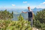 Wirtschafts-Landesrat Markus Achleitner Ein Mann steht in der Natur und zeigt in die Berge im Hintergrund.