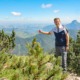 Ein Mann steht in der Natur und zeigt in die Berge im Hintergrund.