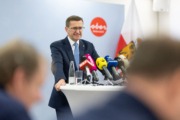 Wirtschafts-Landesrat Markus Achleitner Ein Mann steht an einem Tisch mit Mikrofonen und spricht ins Publikum.