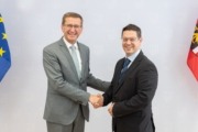 v.l.: Wirtschafts-Landesrat Markus Achleitner und der neue Mechatronik-Clustermanager Wolfgang Steiner. Zwei Herren stehen vor einer Wand und geben sich die Hand.