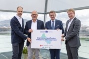 Vier Personen stehen vor der Kamera und halten ein Plakat in der Hand.