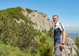 Ein Mann steht vor einem Berg und deutet auf die Natur.