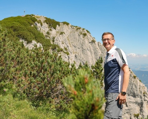 Ein Mann steht vor einem Berg und deutet auf die Natur.