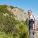Ein Mann steht vor einem Berg und deutet auf die Natur.