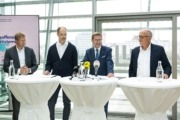 Vier Personen stehen vor stehtischen und sprechen ins Publikum.