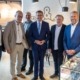 Sechs Herren stehen elegant gekleidet vor der Kamera und lächeln.