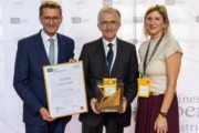 Jurypreis Lebenswerk: Reinhold Klinger (Mitte) mit Wirtschafts-Landesrat Markus Achleitner (l.) und HCM-Beiratssprecherin Martina Hamedinger (FACC AG, r.). Drei Personen stehen vor einer Fotowand und halten Urkunden in der Hand.