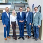 Fünf Personen stehen vor einer Treppe und schauen in die Kamera.