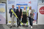 Vier Personen stehen nebeneinander und halten ski in der Hand.