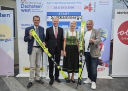 Vier Personen stehen nebeneinander und halten ski in der Hand.