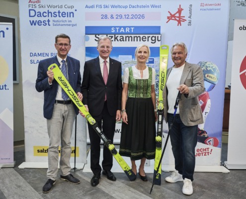 Vier Personen stehen nebeneinander und halten ski in der Hand.