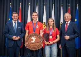 Vier Personen stehen vor einem Vorhang und machen Fotos.