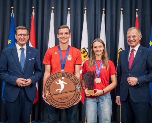 Vier Personen stehen vor einem Vorhang und machen Fotos.